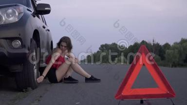女青年坐在汽车附近坏了女青年伤心了女青年碰汽车轮胎女青年碰汽车轮胎女青年